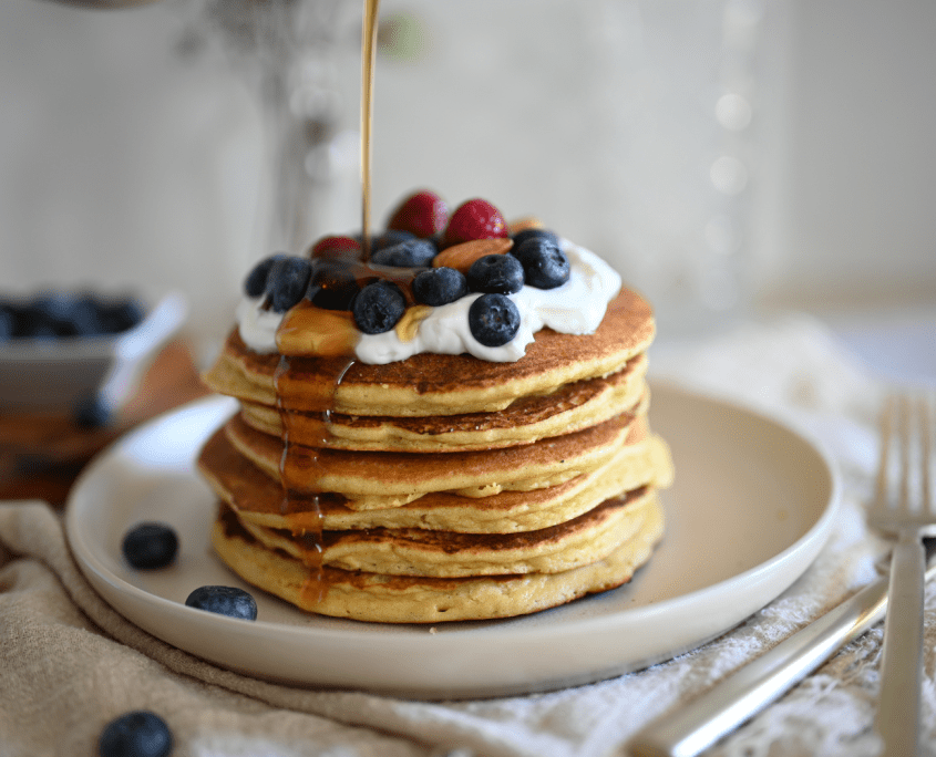 Pancakes mit Ahornsirup und frischen Beeren, die über sie gegossen werden - ein leckerer Stapel Pfannkuchen.