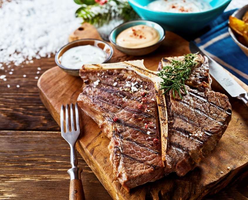 Saftiges gegrilltes T-Bone-Steak auf rustikalem Holzbrett serviert.